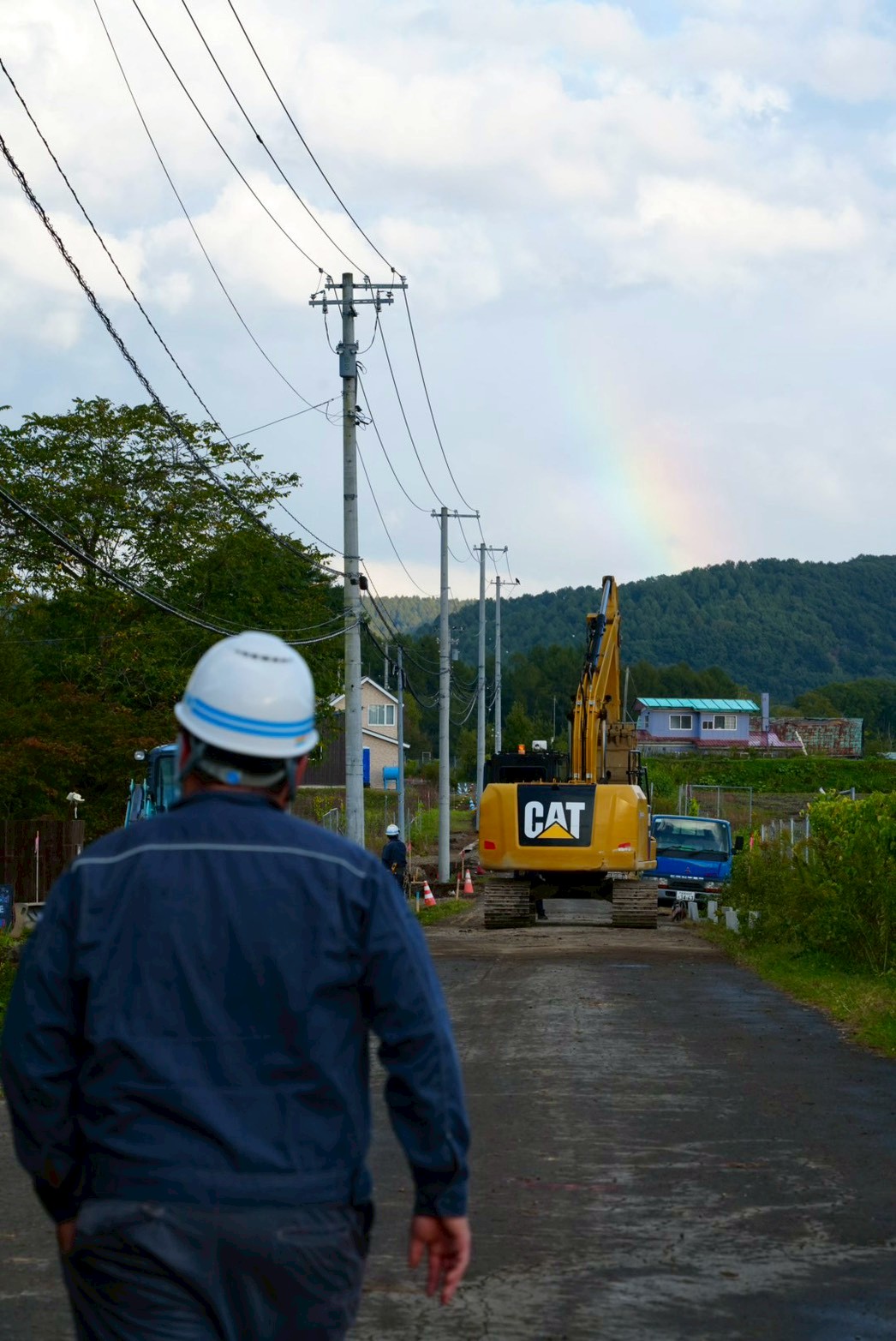 現場へ向かう職人と、虹のかかる厚真の空